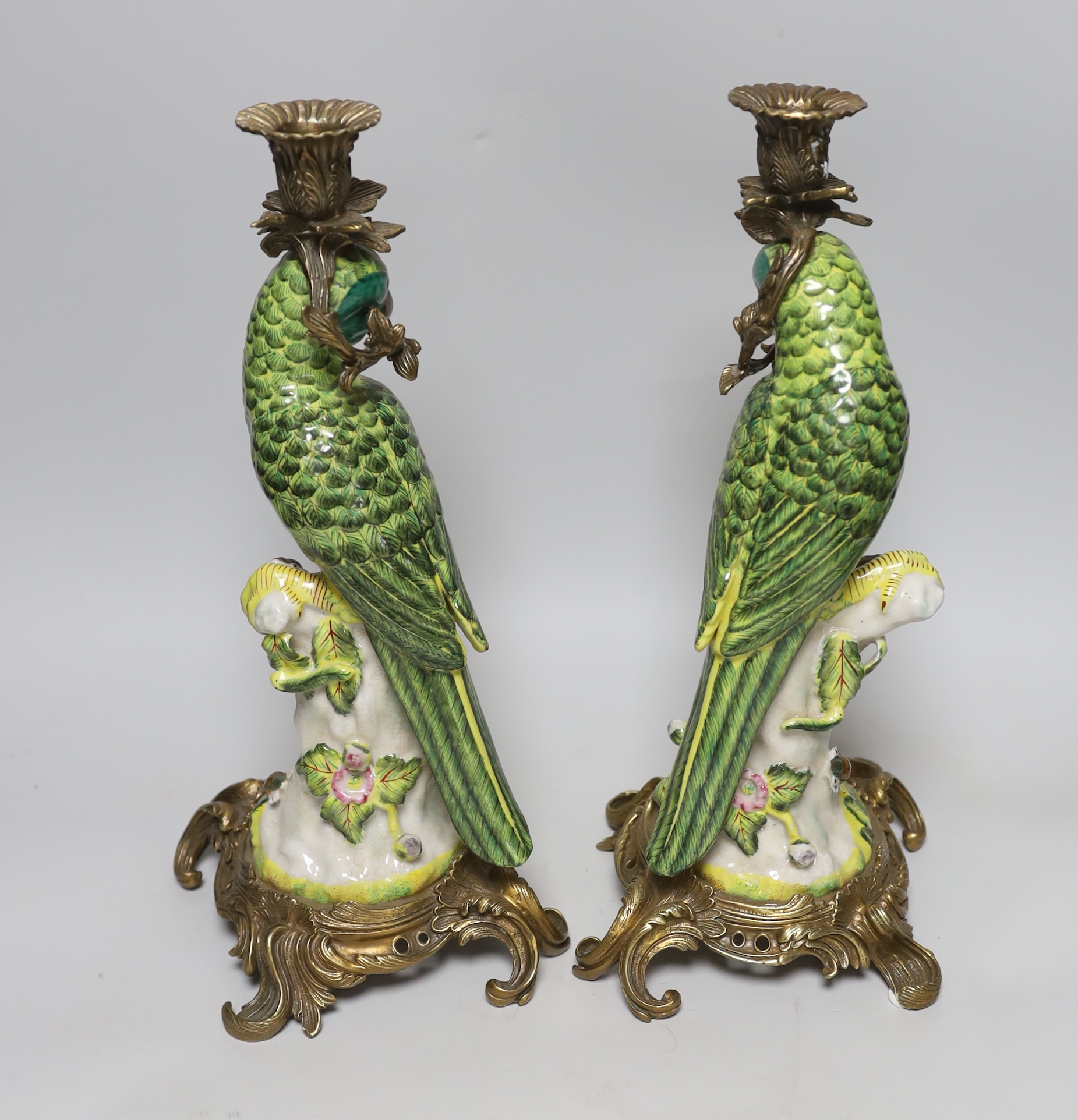 A pair of modern gilt metal mounted ceramic parrot candlesticks, 36cm